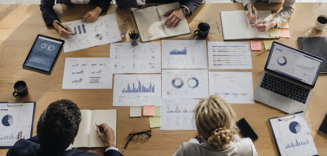Executive team reviewing AI search performance reports alongside traditional SEO metrics during a strategic planning workshop, comparing visibility, citations, and performance data.